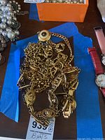 Three gold chain belts laid on blue and wooden surface with medallion details visible