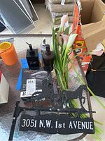 Full lot showing boxed Danfenso hair dryer, three soap dispensers, faux flowers in clear vase, and decorative metal door sign with address