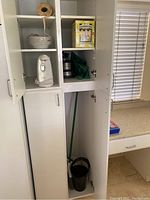 Kitchen cabinet with items displayed inside: blender, can openers, Eggstractor box, cleaning pans and mop handle.
