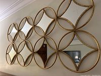 Front view of decorative wall mirror composed of connected circular mirrors with gold-tone framing, showing geometric design and reflective surface.