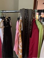 Photo showing five scarves hanging on a clothing rack, various colors and patterns visible.
