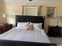 Bedroom setting showing both side tables flanking a bed with leather headboard, demonstrating size and style.
