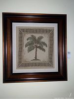 Framed palm tree tapestry hung on wall, showing full piece and frame.