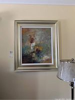 Full view of the framed abstract canvas wall art hung on a beige wall with a silver-toned frame and lamp on the side.
