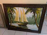 Full view of framed canvas painting showing the sailing boat with sails and surrounding palm trees.