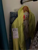 Full view of yellow jacket alongside blue denim jean skirt hanging in closet.