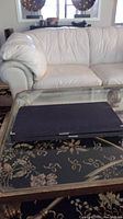 Closed black rectangular box presumably containing the backgammon set placed on a glass coffee table
