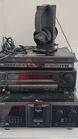 Full view of stacked home audio equipment including JVC DVD player, Kenwood receiver, Hitachi VCR, Sony CD player, and Sony wireless headphones on transmitter stand.