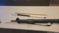 Two pool cues and black carrying case displayed on table showing size and case details