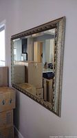 Front side view of large rectangular framed wall mirror against beige wall showing ornate metallic frame and reflective glass.
