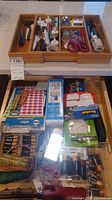 Full drawer view showing assorted items including tapes, batteries, scissors, and water filter