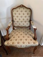 Full front view of carved wood framed armchair with tapestry upholstery