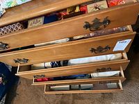 Five wooden dresser drawers partially open, showing the contents of multiple drawers filled with small boxes and trays of jewelry.