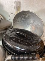 Black enamel roasting pan with lid showing handle and speckled pattern