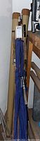 Overview of six rods leaning against wall with three cardboard tubes behind.