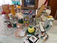 Wide view of all kitchenware items including glassware, appliances, tins, and tools on a table