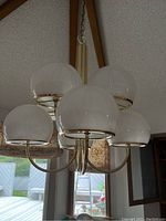 Close-up of five frosted white glass globes and curved brass arms