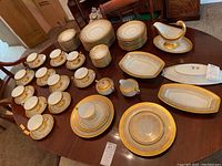Full table view of 80-piece set showing stacks of plates, bowls, cups, saucers and serving pieces