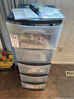 Front view of five-drawer plastic storage cabinet with top and visible contents in upper drawers