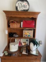 Overview of wooden shelf showing multiple vintage purses, a hat on mannequin head, jewelry boxes, and accessories.
