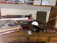Shelf and desk overview showing leather pouch, belts, canvas bag, tape reel, level, magazine and newspapers