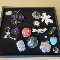 Full lot of assorted pins and pendants displayed on black velvet background