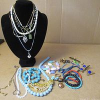 Full lot photo showing necklaces displayed on bust and spread out bracelets, rings, and earrings on table