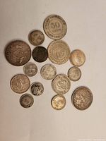 Top-down view of 14 silver coins on white background
