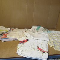 Overview of assorted hand-knit doilies and textile pieces in a pile, showing varied patterns and colors.