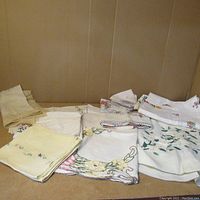 Overview photo showing multiple assorted vintage textiles and hand-knit doilies spread on a surface.