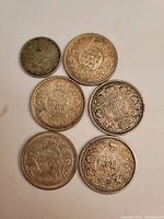 Six assorted large silver coins from India dated 1913 to 1930, reverse sides with 'One Rupee India' inscription and floral design.