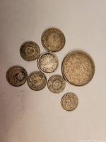 Top view showing full set of eight assorted Japanese silver coins, arranged on a white surface.