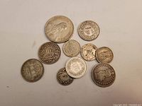Top-down view of the 10 silver coins arranged on a flat surface showing fronts with numeric values and designs.
