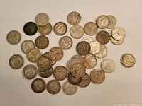 Overview photo of approximately 39 silver shilling coins from British and Commonwealth origins scattered on white background