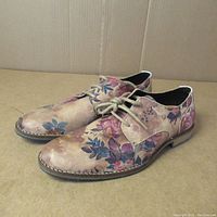 Pair of men's floral design Bull Boxer shoes shown side by side on cardboard background, showing wear and floral patterns.