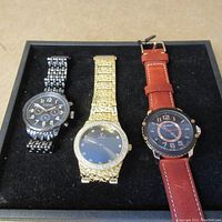 Set of three men's wristwatches in display box showing overall condition and appearance
