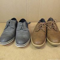 Front view of two pairs of men's shoes size 10, one gray and one light brown.
