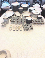 Wide shot of the china set spread out on a table showing all types of pieces including plates, bowls, cups, saucers, covered dishes, and small bowls.