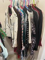 Photo showing assorted ladies jackets, dresses, and sweaters on hangers in a closet, mostly size large, with various patterns and colors.