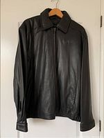 Full front view of the black leather jacket hanging on a hanger to show overall condition and style.