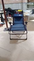 Front view of blue folding lounge chair with attached side table on left side
