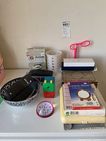 Photo showing assembled various items including wood inlay jewelry box, cosmetic mirrors in packaging, reading glasses, travel clock radio, pencil sharpener, ballpoint pens and pen cases.