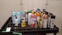 Photo showing multiple spray paint cans on black rack with various colors, including minis and larger spray cans.