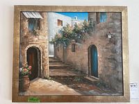 Front view of the framed acrylic painting of a Mediterranean street scene with flowers and blue doors.