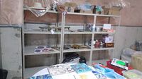 Side view of three metal utility shelving units in basement, shelves holding various household items.
