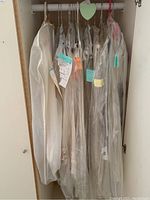Table linens hanging in closet covered mostly in protective plastic covers with tags