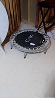 Mini trampoline showing the CAP branded black jumping mat and metal frame with legs, photographed in a basement setting.
