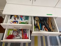 Three open drawers showing kitchen utensils, cake decorating tools, cutlery, and kitchen gadgets