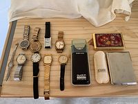Overview of ten watches lined up with Swatch box, cases and lighter