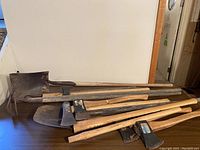 Photo showing axes and gardening shovels laid out on a table